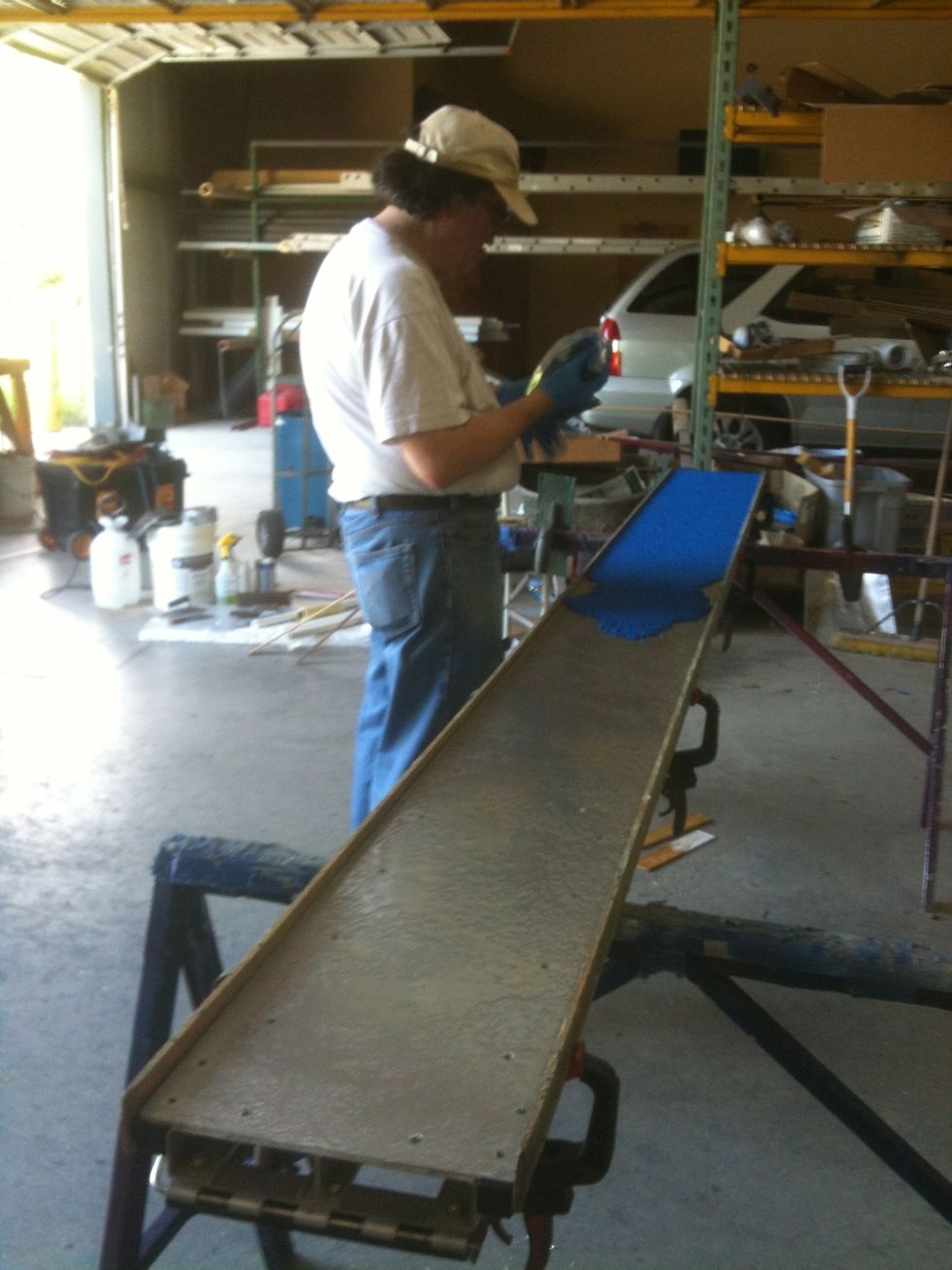 Spread the granules on the primed surface with a clean trowel. A form is being used to contain the rubber binder mixture.