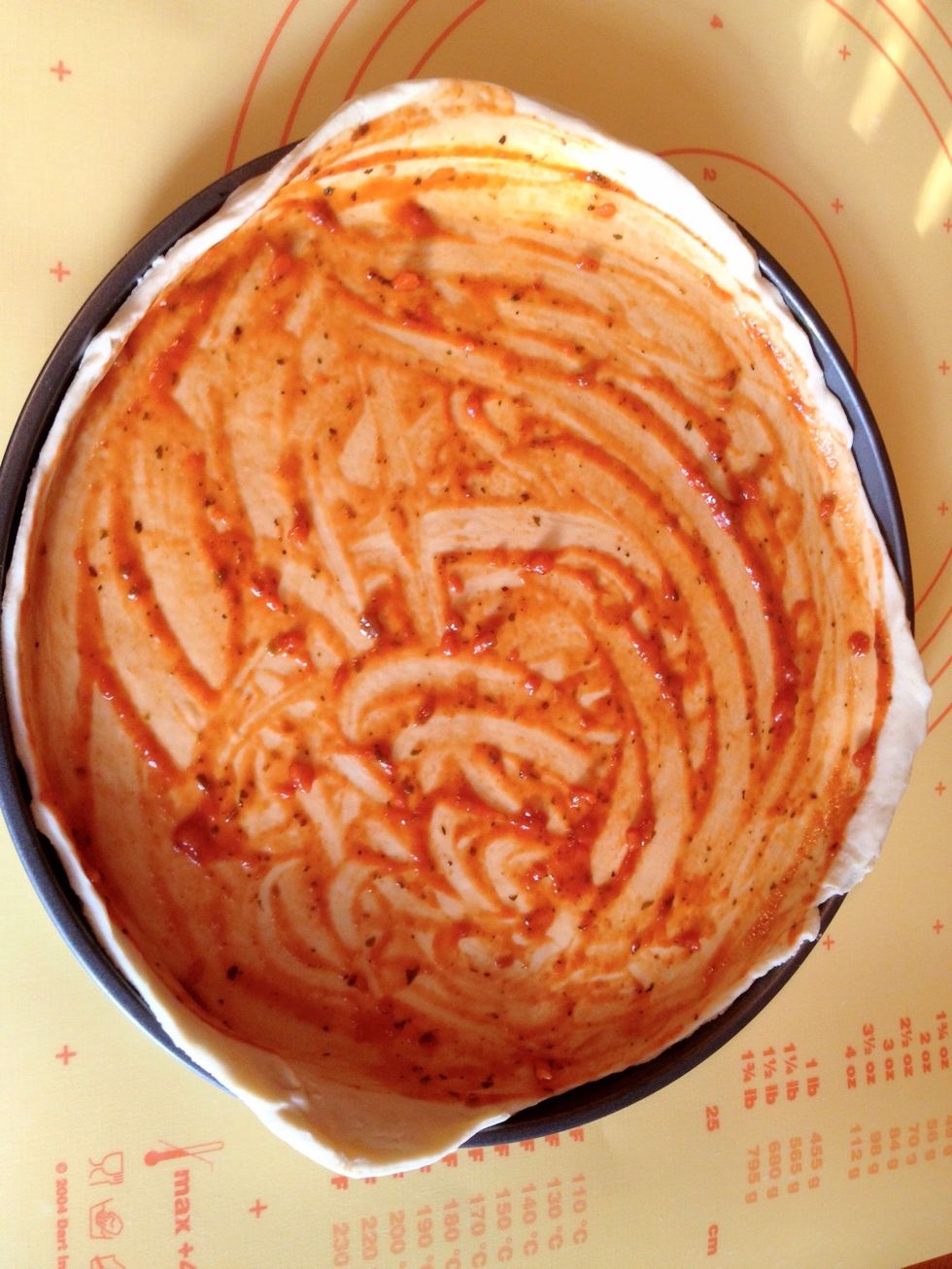 Spread the ketchup or tomato sauce over the dough.
