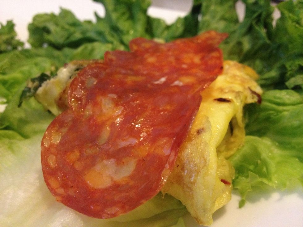 Spread the lettuce wide and Place one-half of the egg in the middle. Place a slice of salami on the egg.