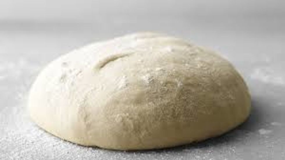 spread the pizza dough into a large circle that is still thick