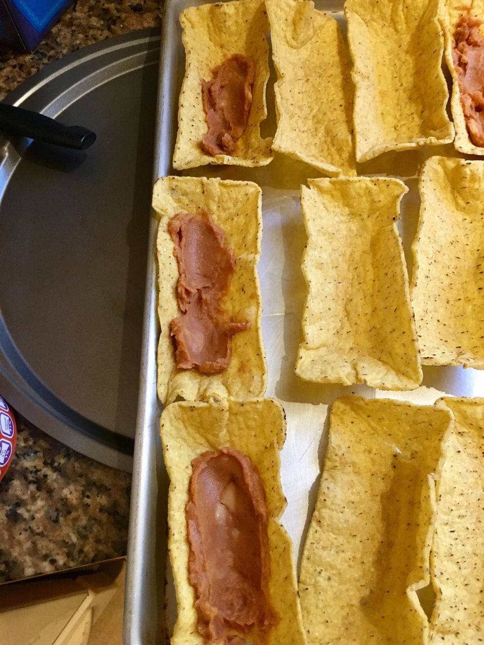 Spread the refried beans on the taco boat shells