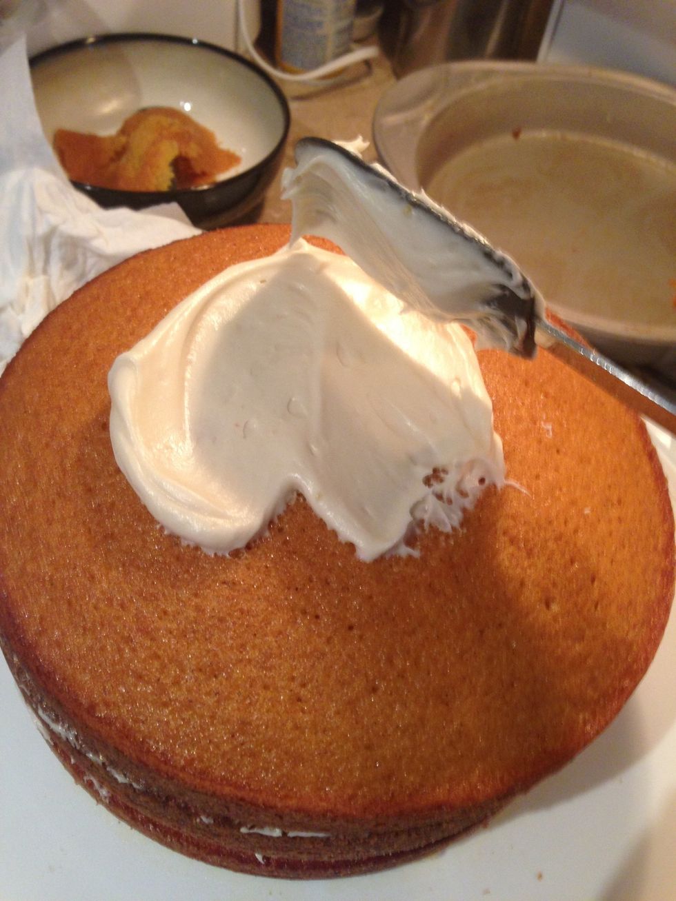 Spread the remaining generous amount of frosting all over the top and around the sides of the three layered cake.