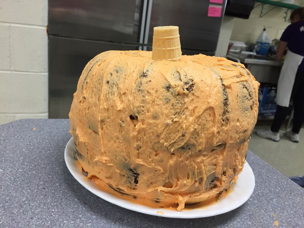 Spread the rest of the icing all around the top and side of the entire "pumpkin" and place the cone in the hole on the top