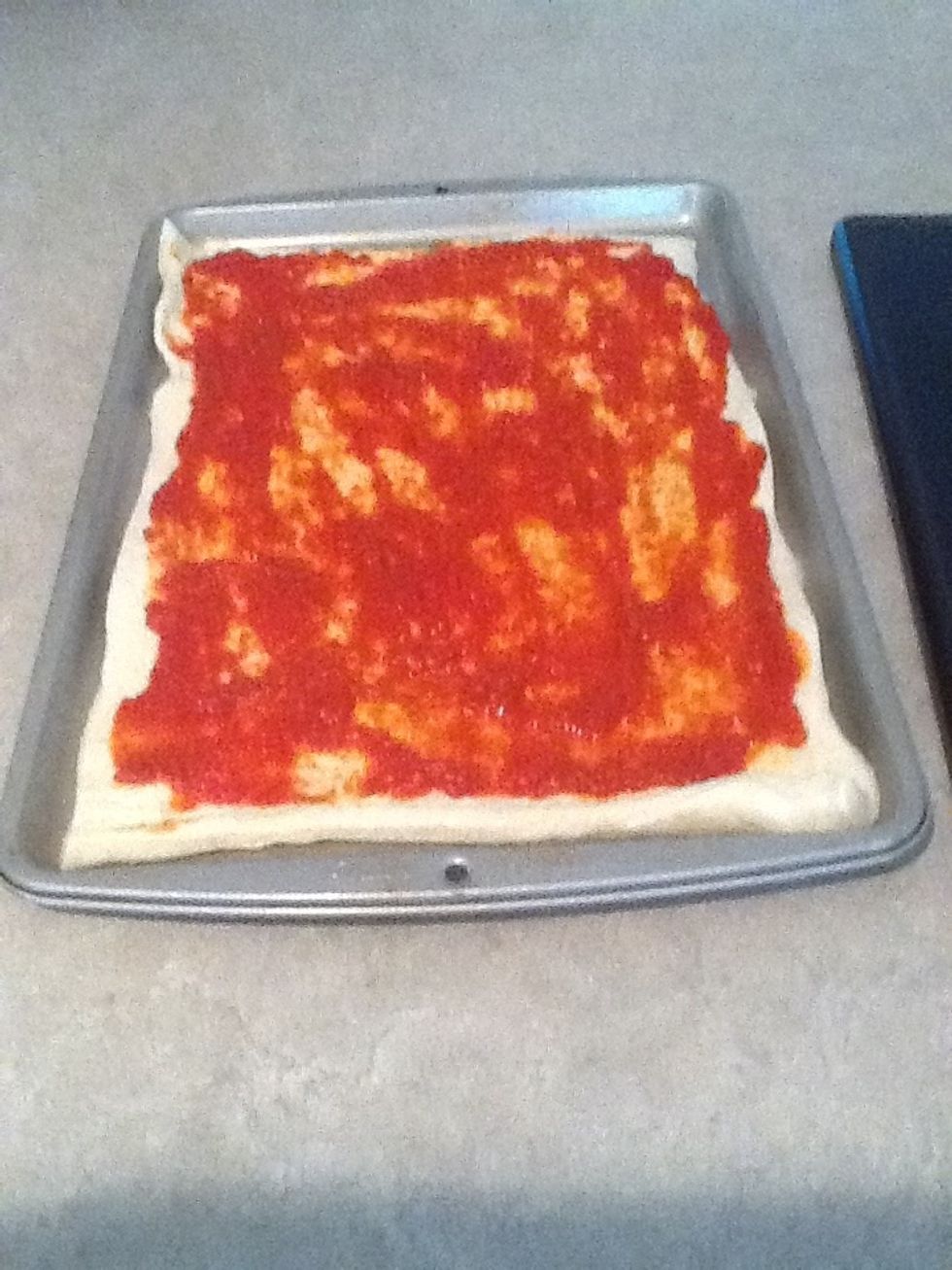 Spread the sauce with a spoon across the dough. Spread it evenly.