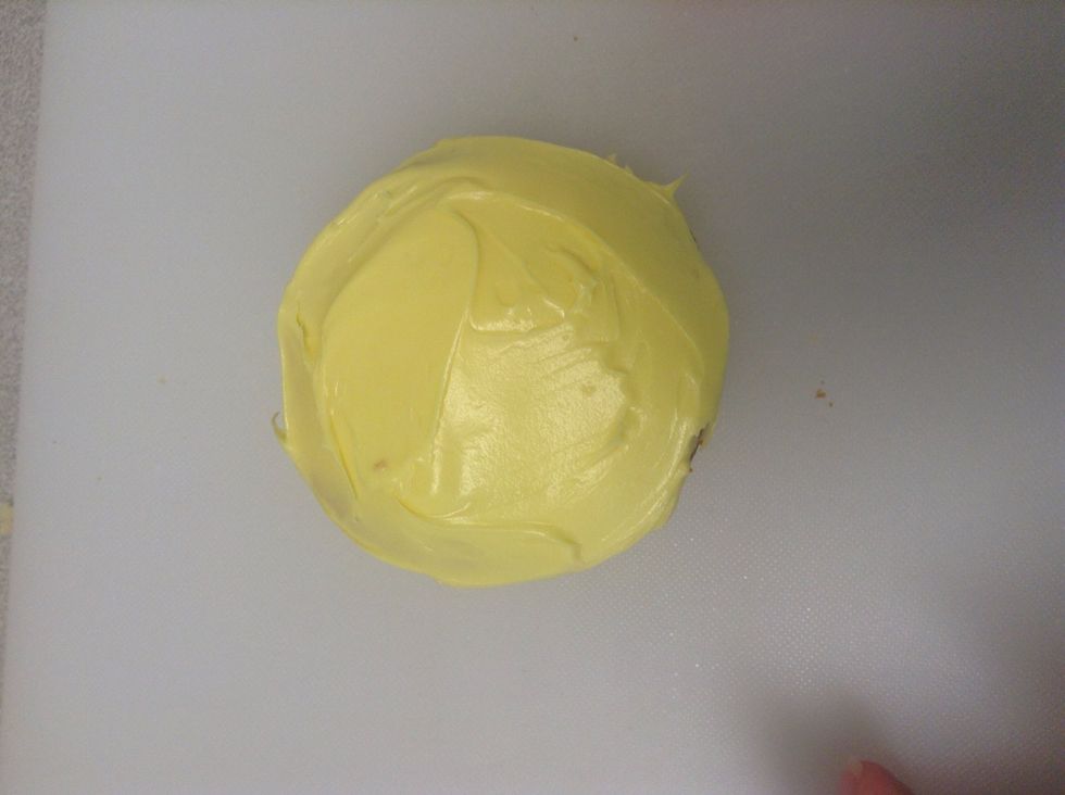 Spread the yellow icing on the cupcake until smooth with a knife