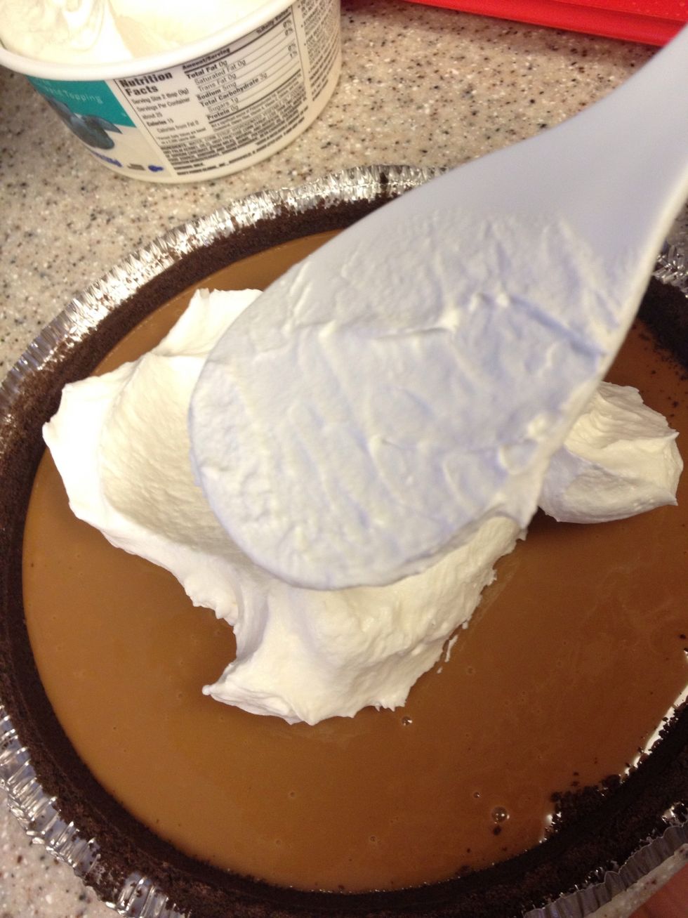 Spread topping gently over caramel. Caramel is still soft, but it has a thicker consistency that the cream. Therefore spreading the whipped topping is relatively easy. (I use refrigerated topping.)