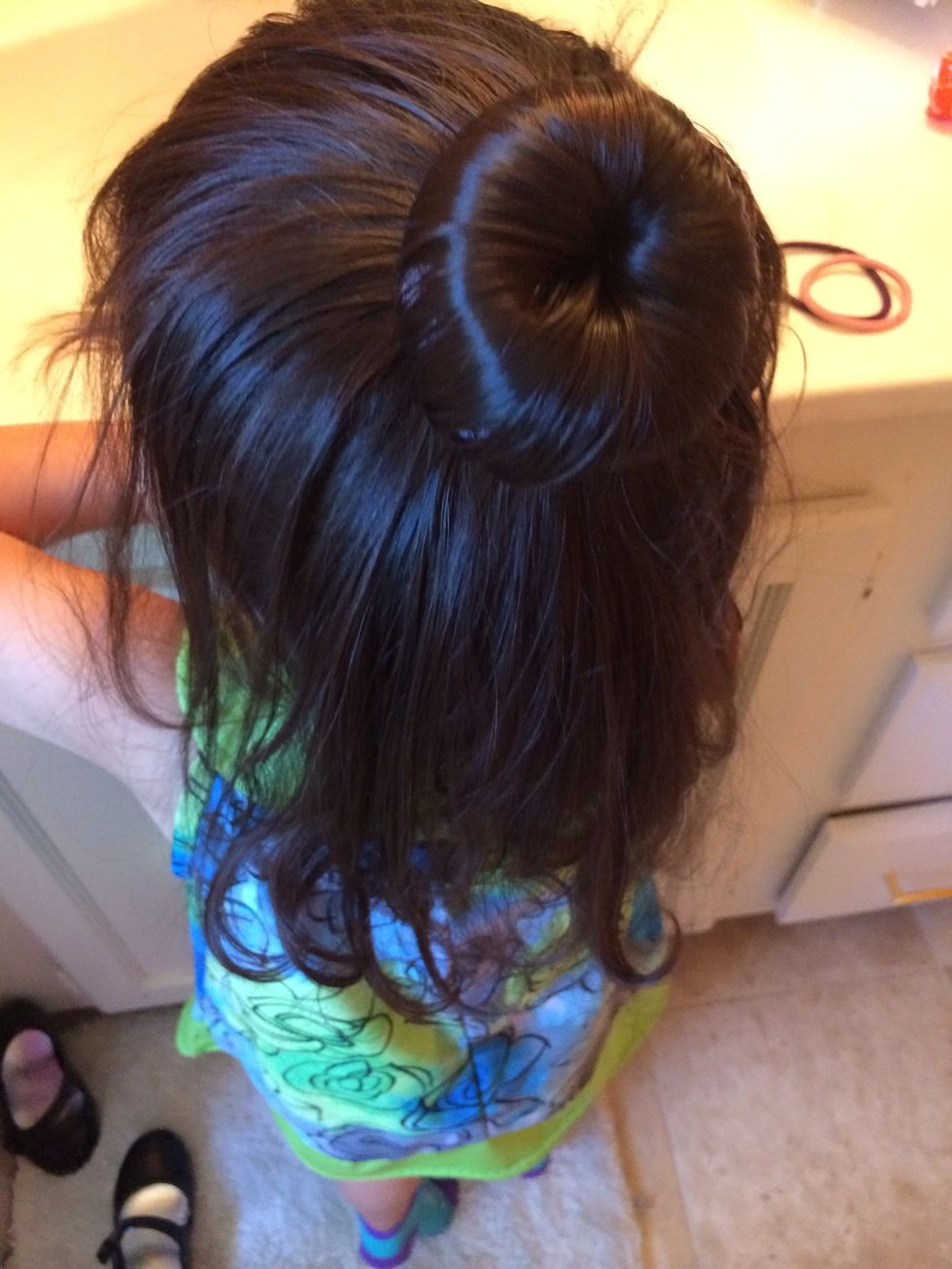 Spread your hair and cover the sock or donut and put the elastic on top of it