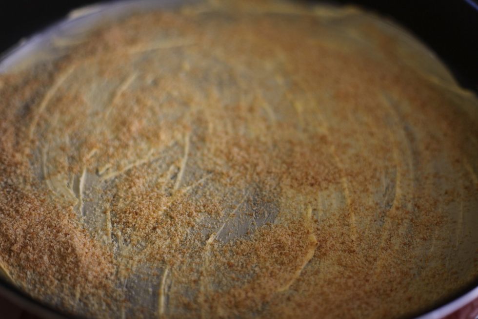 Sprinkle about half a cup of bread crumbs on your buttered or gheed (new word) tray and just shake it around until the crumbs stick themselves to the butter.