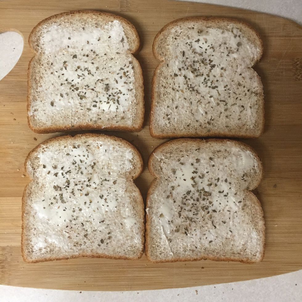 Sprinkle basil, onion powder, and garlic salt onto the buttered slices