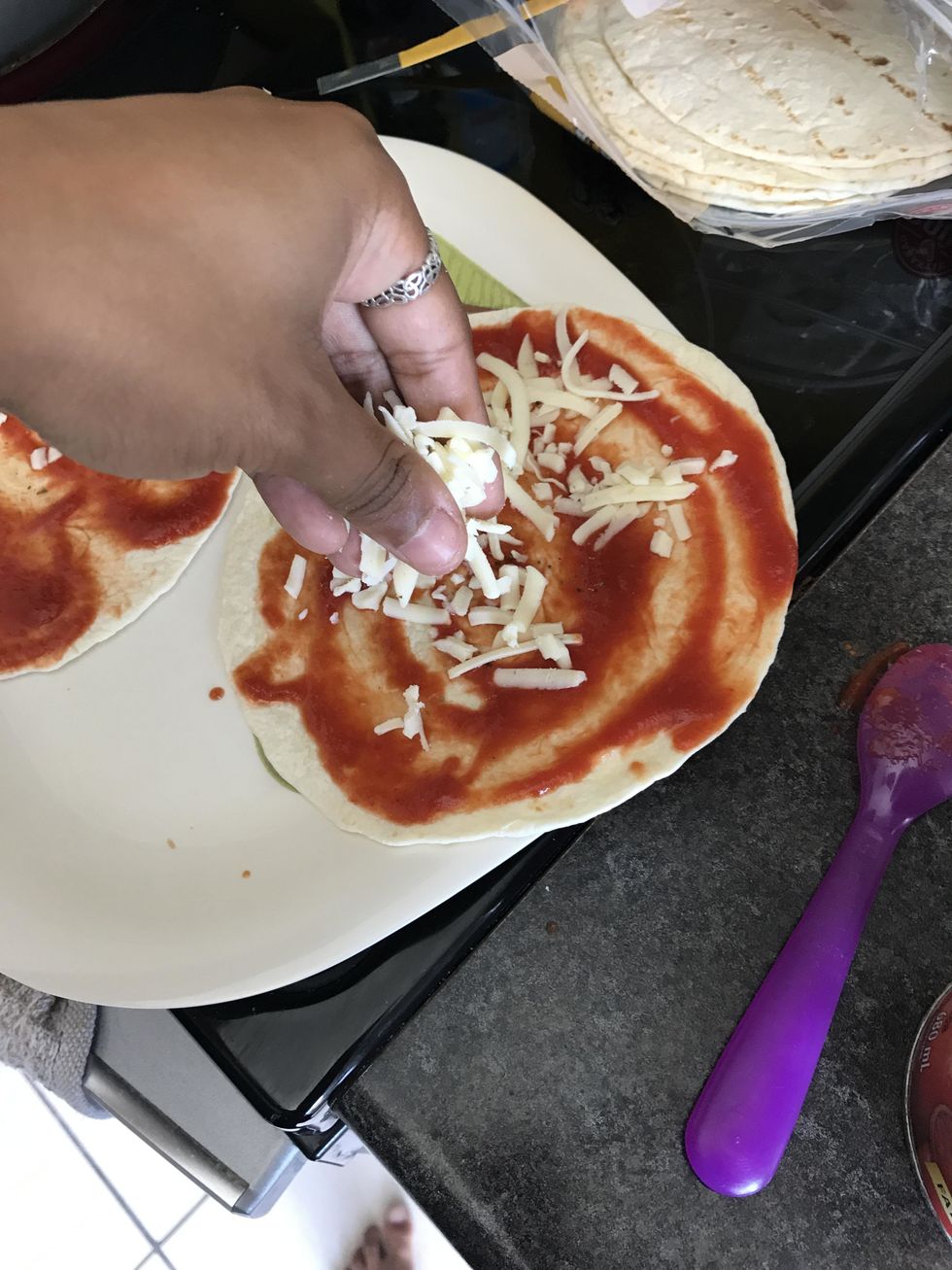 Sprinkle cheese on top of the sauce on the bottom tortilla.