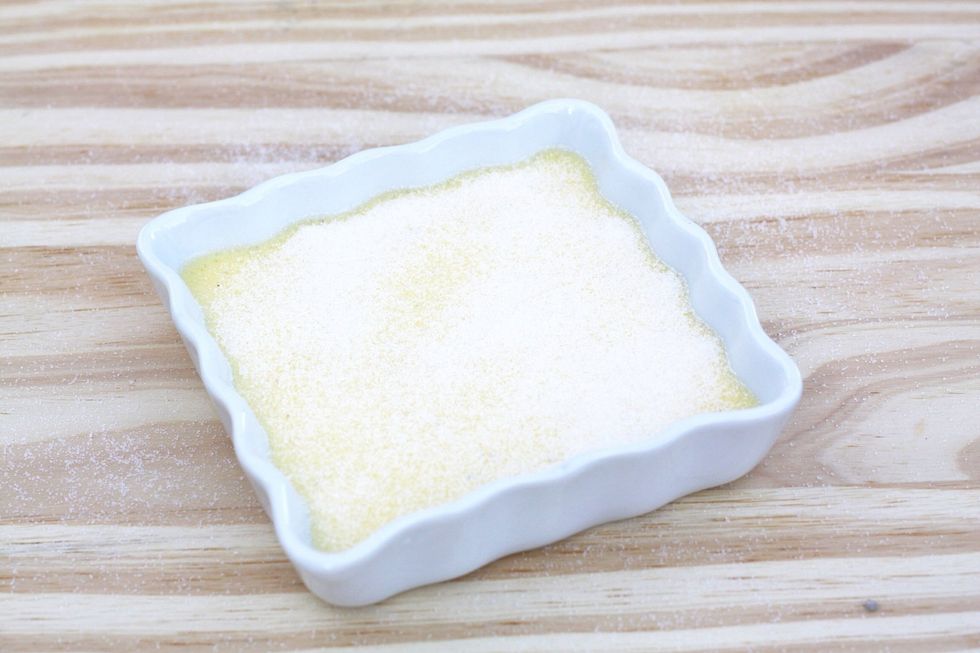 Sprinkle granulated sugar evenly over the top of the cr\u00e8me br\u00fbl\u00e9e, shaking the dish lightly if needed. The use of a sugar shaker is recommended.