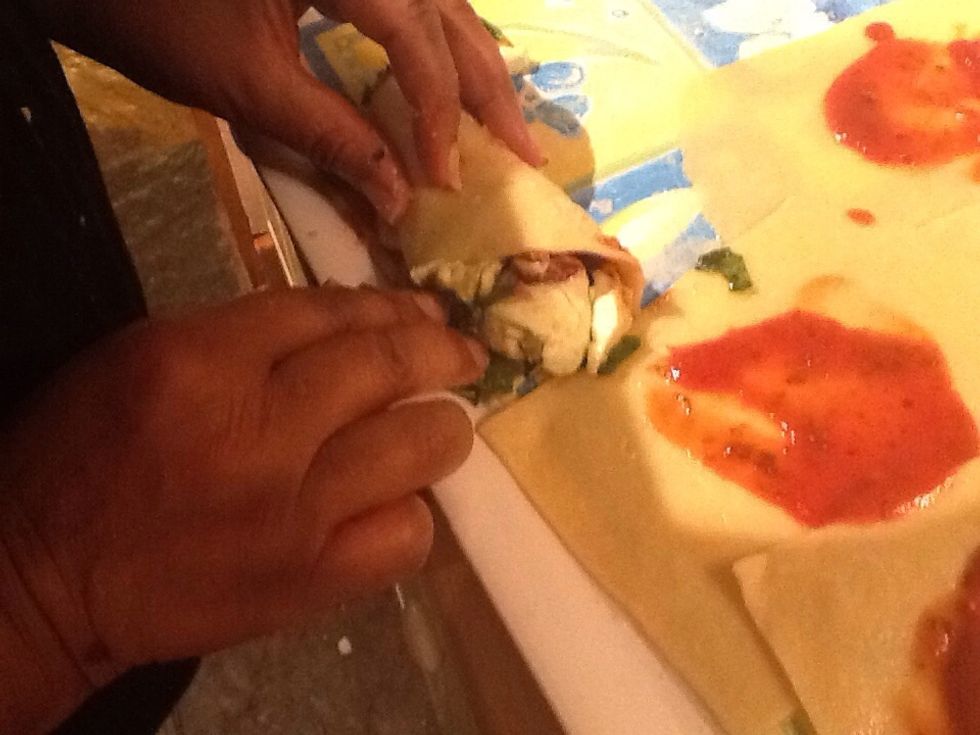 Sprinkle parmesan on tray. Then place pasta squares onto tray. Spoon a bit of tomato sauce onto pasta squares. Then spoon filling onto square and roll.