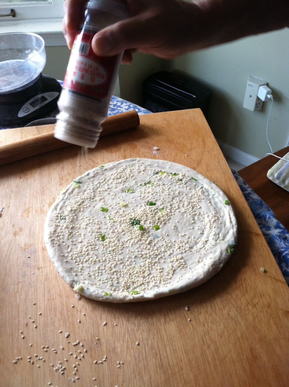 Sprinkle sesame seeds generously onto the wet surface of the pancake. Use the rolling pin to gently press the seeds into the pancake.