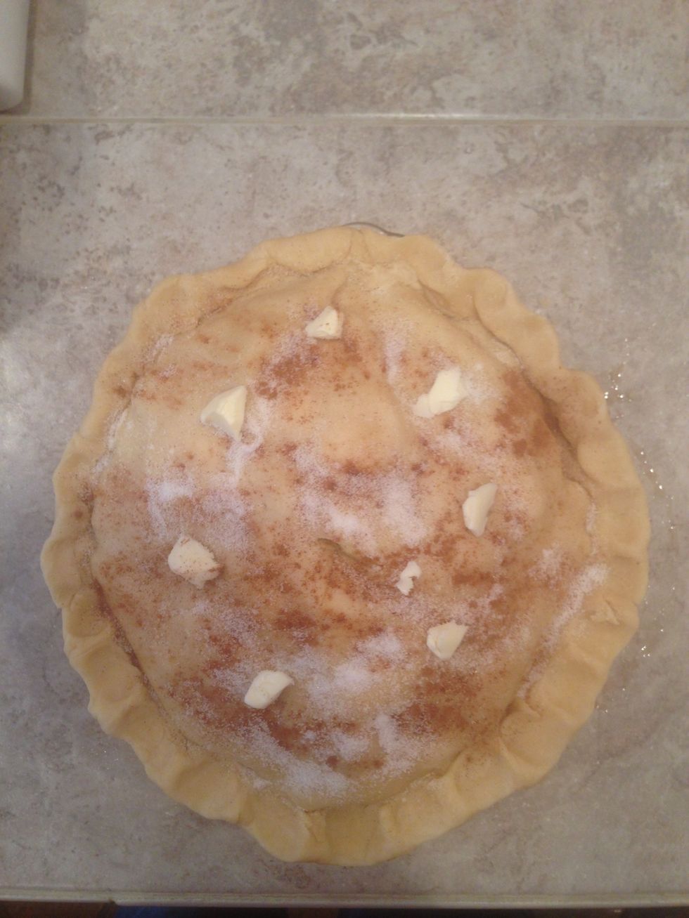Sprinkle sugar and cinnamon on top of the pie along with a few small slices of butter.