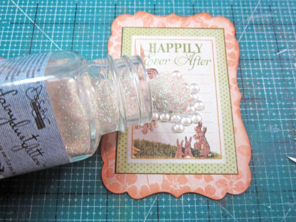 Sprinkle the glitter and dew drops or anything that you would like to be held in the shaker over the top of the frame/label picture.
