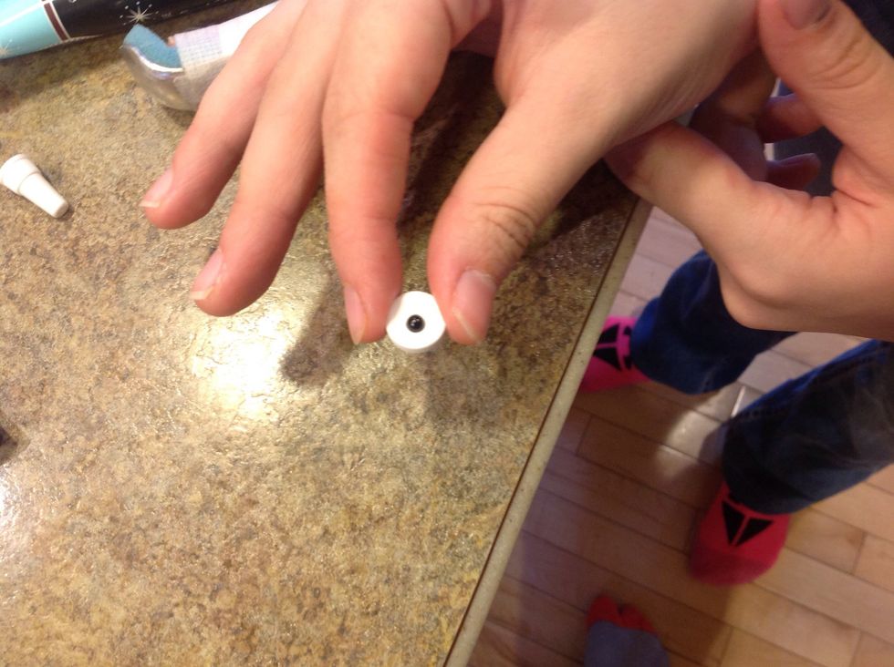 Squeeze a black dot of frosting on Smarties, to use as glue