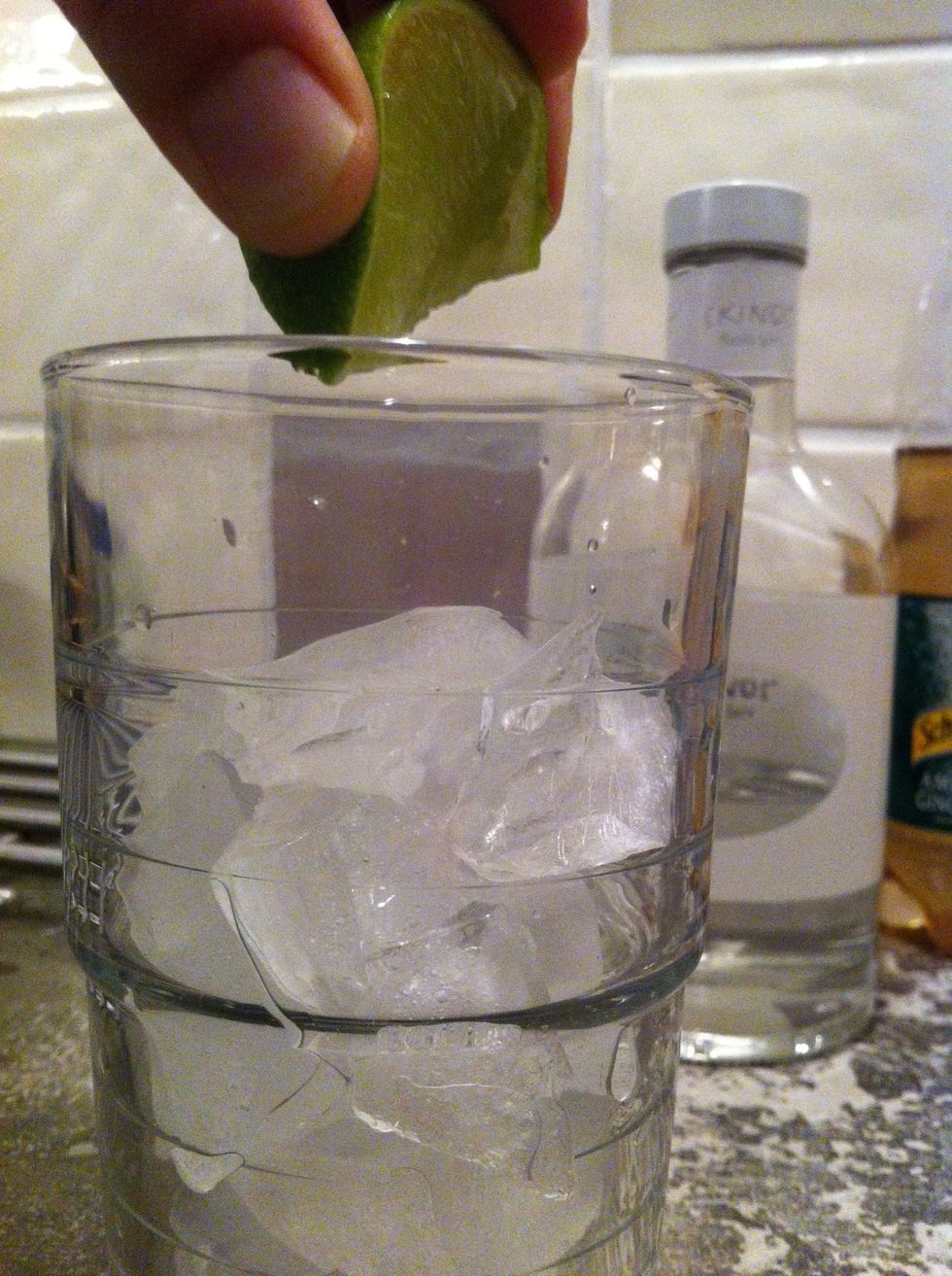 Squeeze a lime wedge on top of the ice and then drop into the glass
