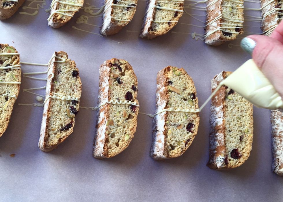 Squeeze bag to drizzle white chocolate on biscotti.