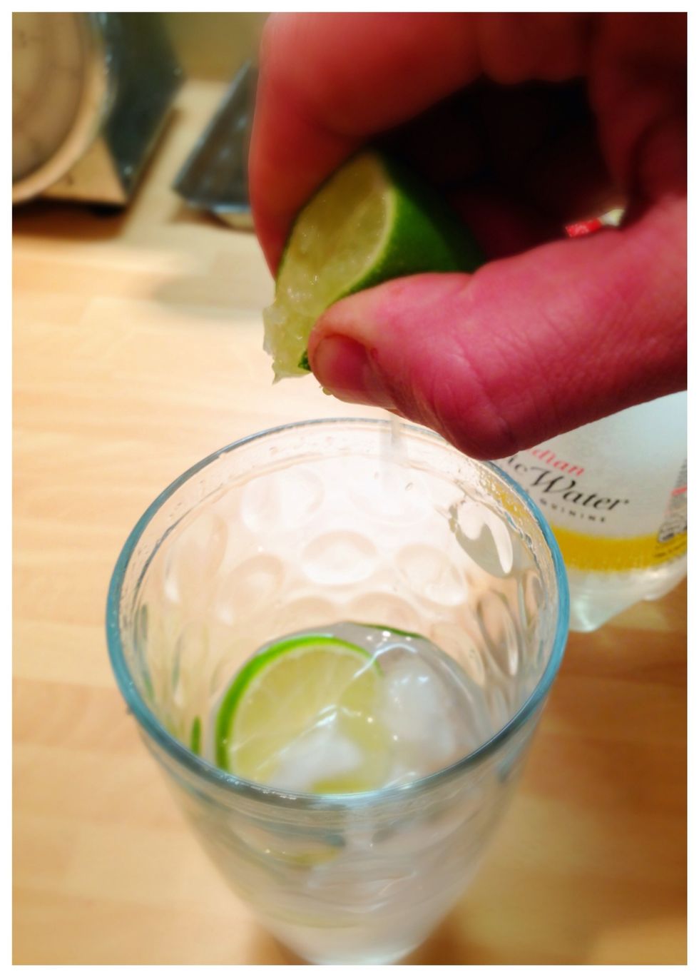 Squeeze the remaining juice from the lime quarter into the gin!