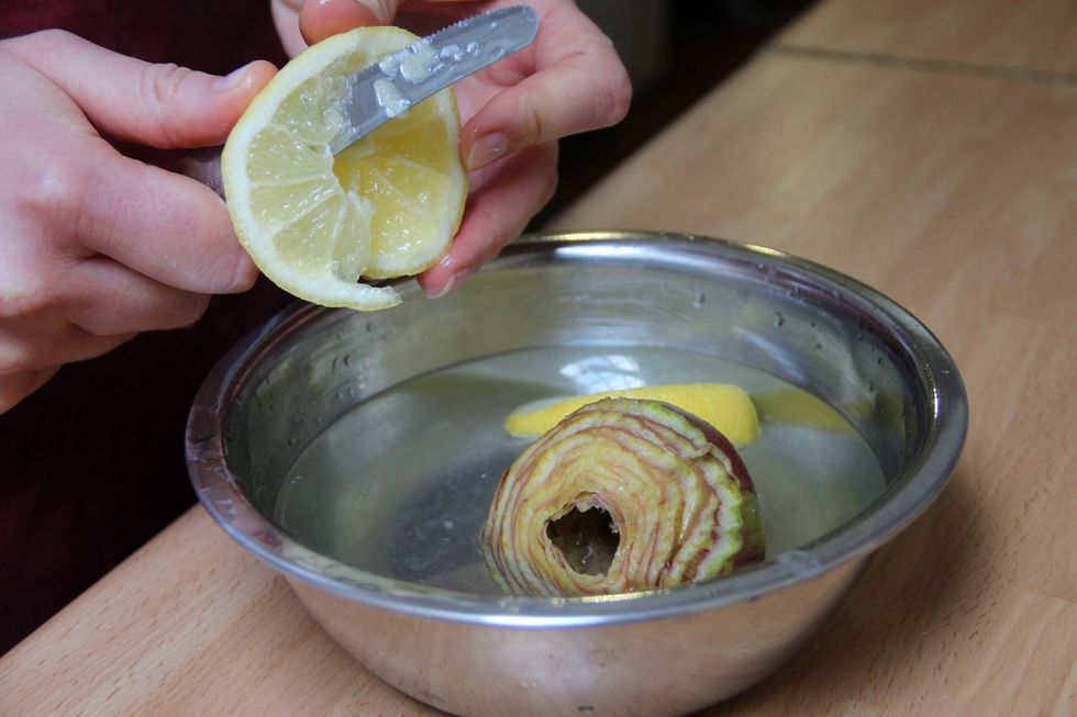Squeeze the two lemons into 2/3 quarts of cold water and throw in the lemons. Keep the prepped artichokes in the water till your ready to cook them...this prevents them from turning dark.