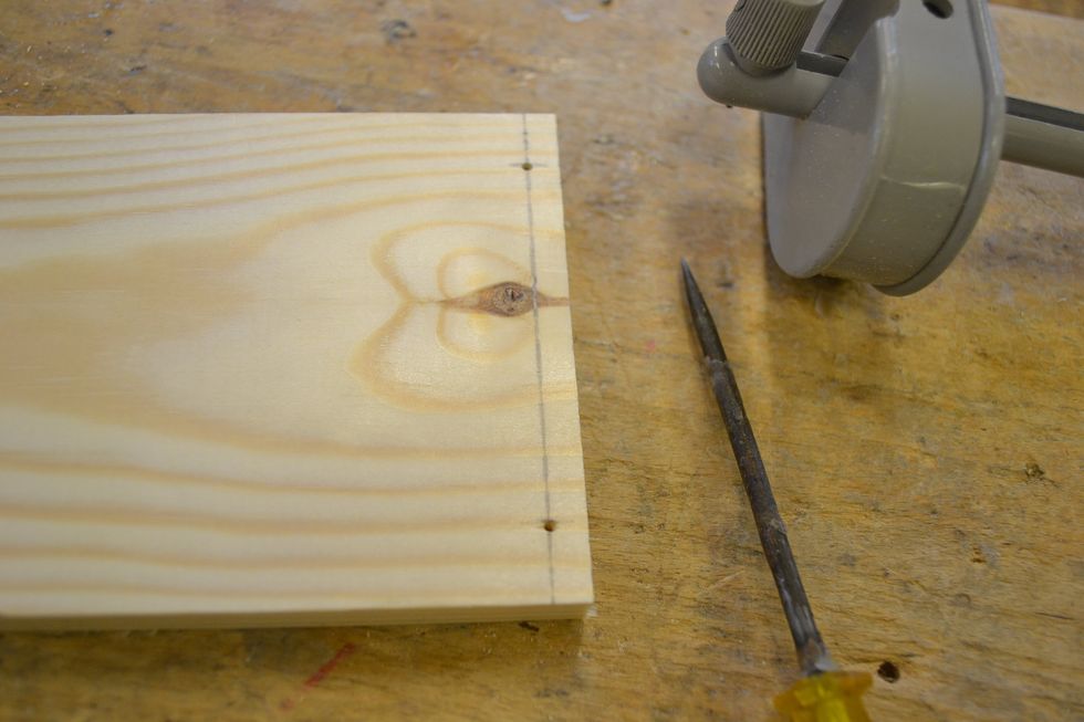 St\u00e4ll in strykm\u00e5ttet p\u00e5 12mm och m\u00e4rk ut tv\u00e5 sm\u00e5 streck fr\u00e5n var sin sida enligt bild och g\u00f6r h\u00e5l med syl. OBS Endast de 2 l\u00e5nga br\u00e4dorna skall m\u00e4rkas och borras, inte de korta.