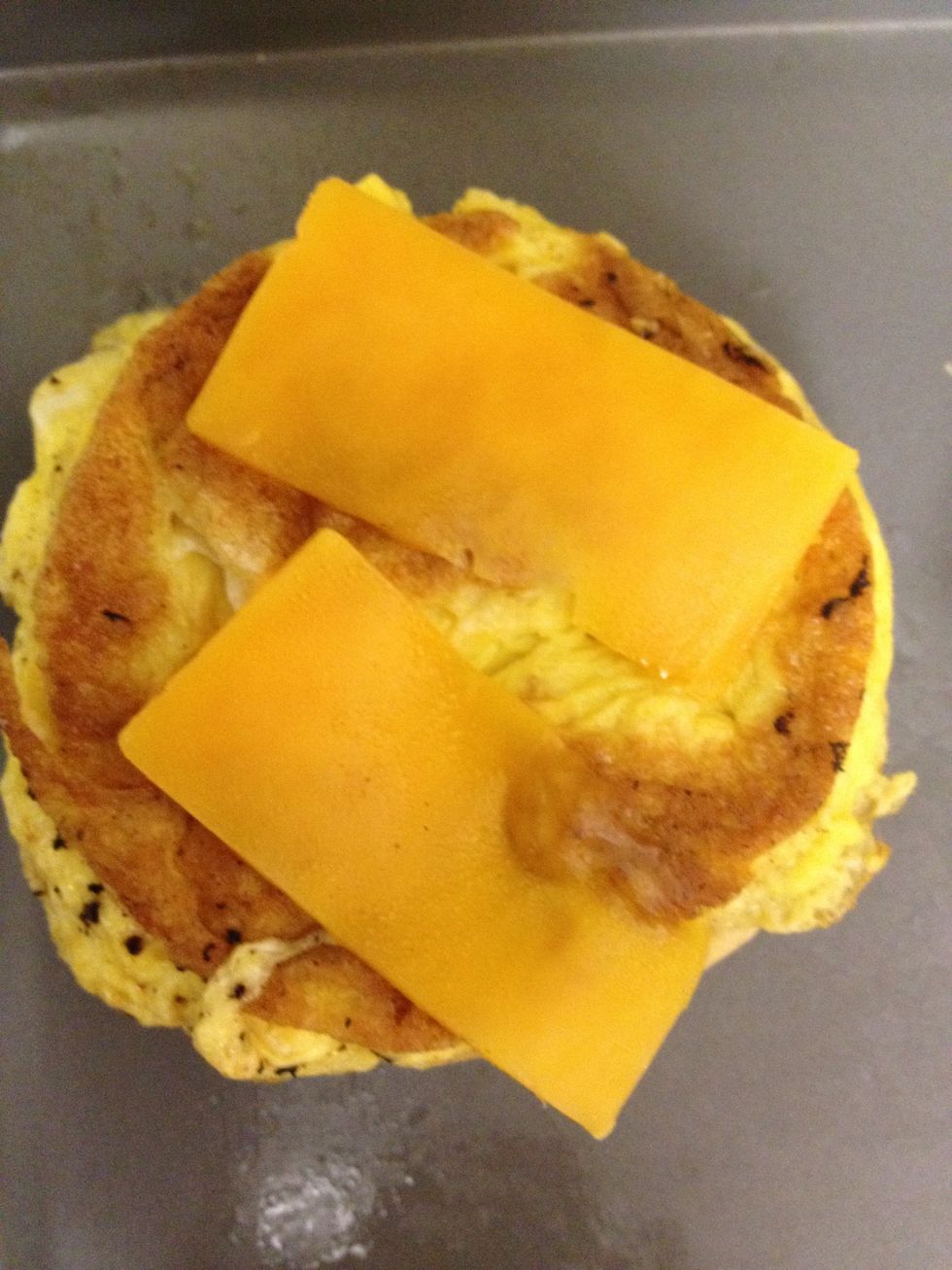 stack the cheddar cheese slices on top of the egg, that is stacked on top of the biscuit - place on a cookie sheet and place in the broiler until cheese is melted.
