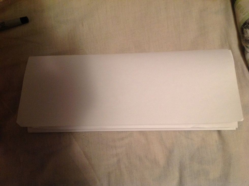 Stack the four pieces of paper together and fold them length wise.