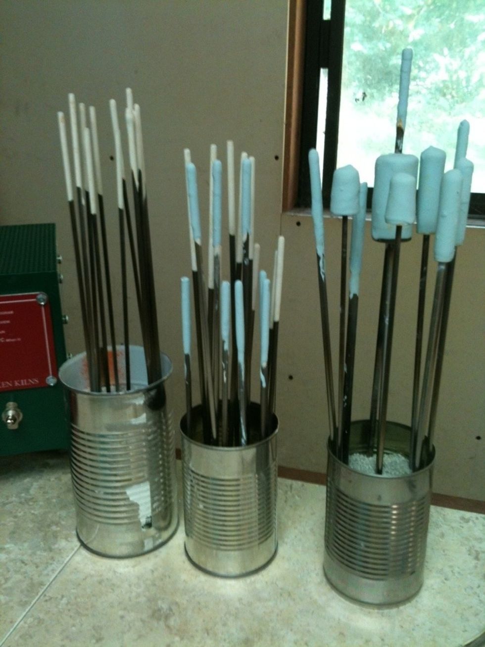 Stainless Steel Mandrels dipped in Bead Release. The molten glass will be wrapped onto the bead release, then when cooled, the bead release melts/cracks off the glass & mandrel. Mandrels are reused.