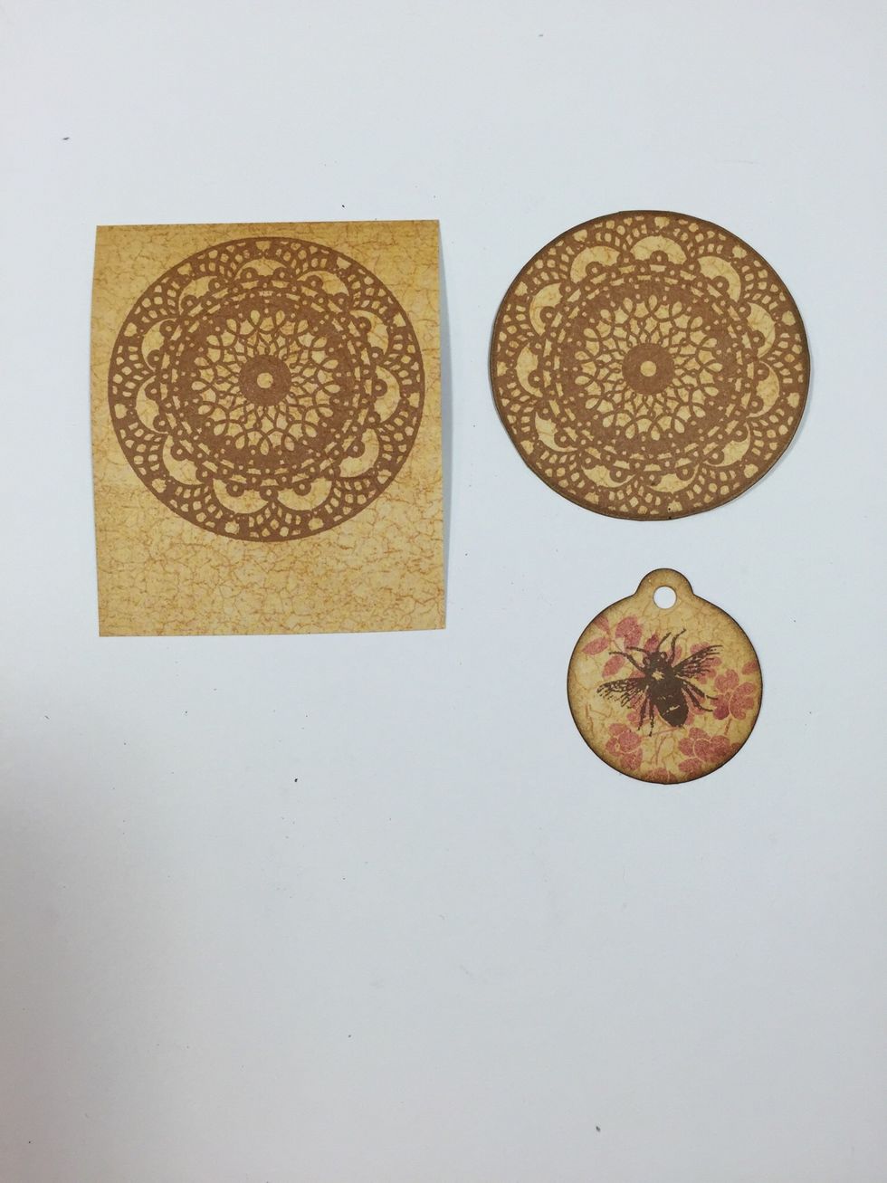 Stamp a doily image onto pattern paper using a light brown ink. Cut out and ink edges. Stamp the small tag with layered stamps. I used the "Honey Happiness" stamp set by My Mind's Eye.