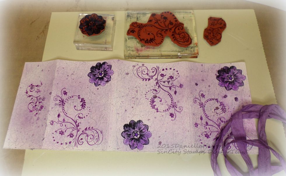 Stamp the swirls and flowers on to the cover. Stamp the swirls in purple and the flowers in black. Color the flowers in with a purple marker.