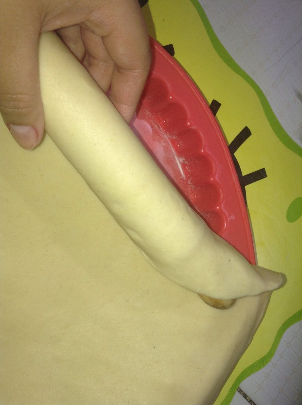 Starr placing the roller pin with the dough wrapped on any edge of the mold and start rolling till the dough is finally on top of the mold.
