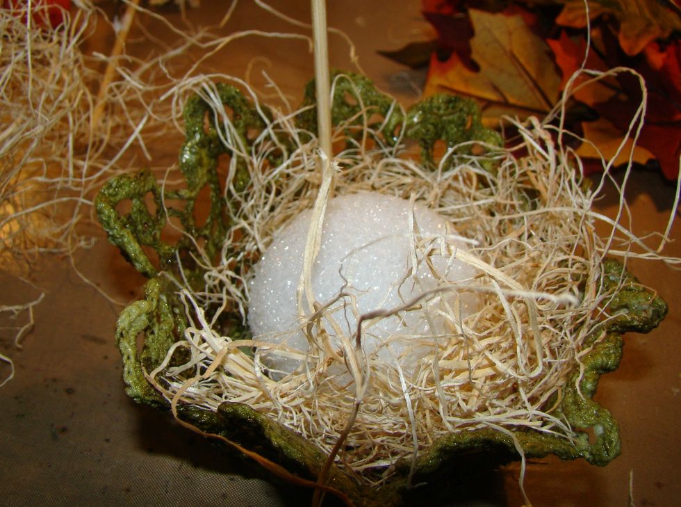 Start adding your filler by using your glue gun. Use Spanish Moss or raffia filler, whatever is your taste. Cover the entire ball and all the sides.