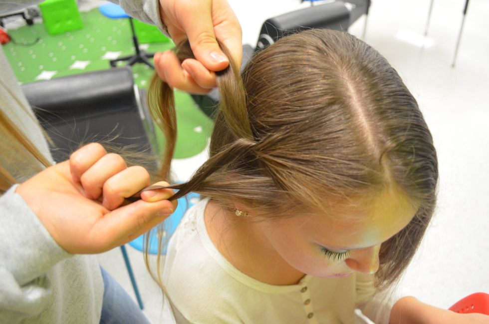 Start an inside-out or "Dutch" braid. Make sure that you are picking up equal amounts of hair and keep the braid tight.