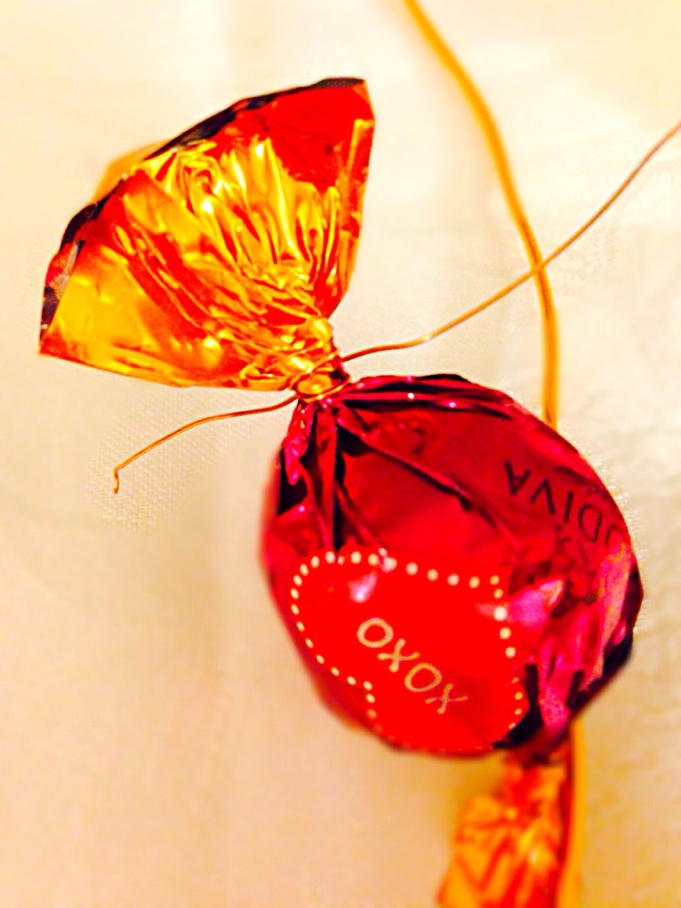 Start attaching your candy by wrapping thin wire around one end and attaching it to the thick wire