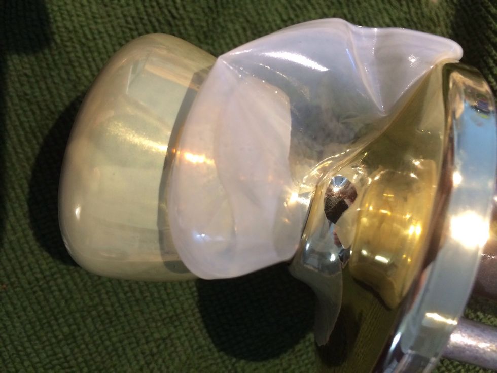 Start by breaking the lacquer lauer with the edge of a screwdriver and use a spudger to remove the rest. Pieces like to linger around the screw holes and on the joint between base and knob.