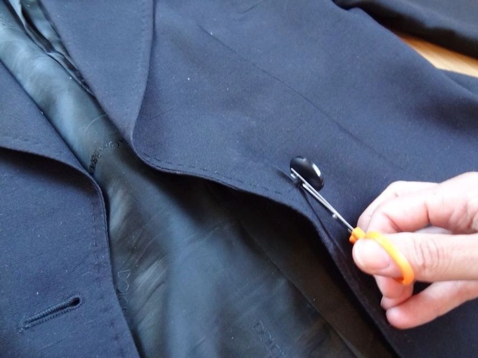Start by cutting off existing buttons and removing any excess thread. Coat fabric tends to be thicker, so thicker thread is necessary. Thread your needle and double tie a knot to close the loop.