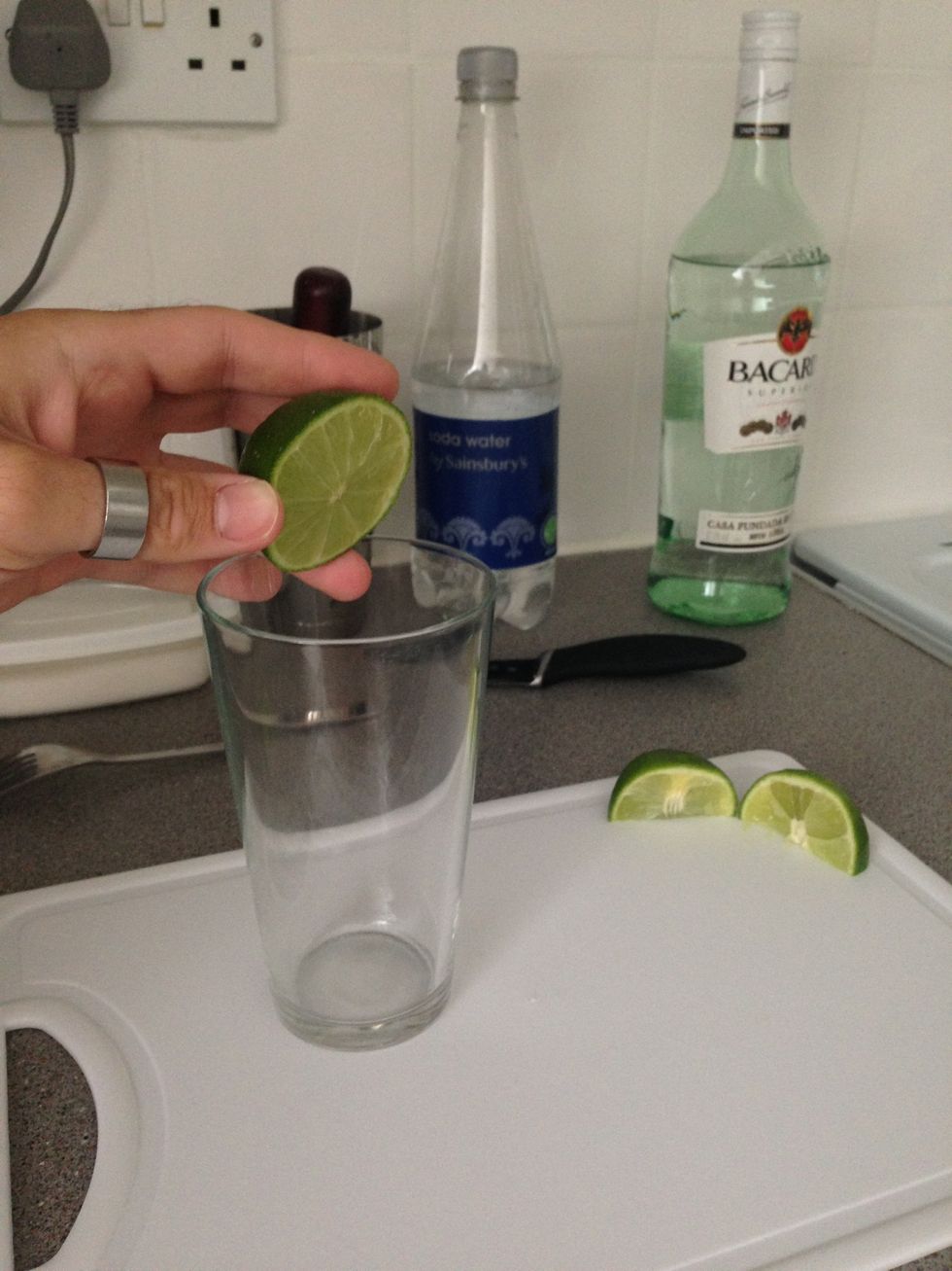 Start by cutting the lime into 1 half and 2 quarters. Squeeze 3/4 of the lime into a Collins glass (Highball glass). Save the other 1/4 lime.