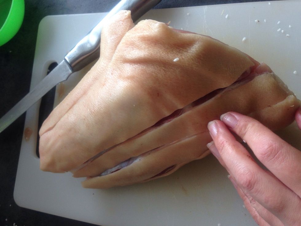 Start by cutting the skin to form the rinds. Cut all the way through the fat to the surface of the meat. At one place cut all the way to the bone. This reduces the cooking time.