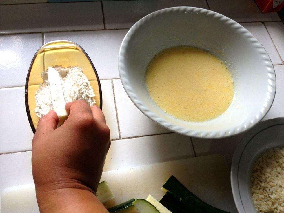 Start by dredge the zucchini to the flour