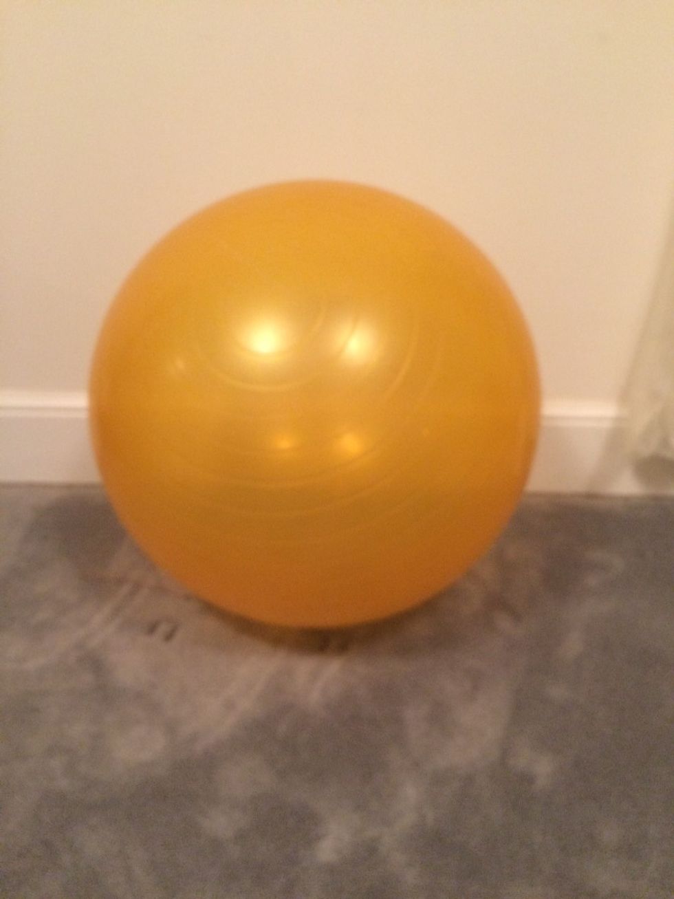Start by getting an exercise ball and a flat surface.