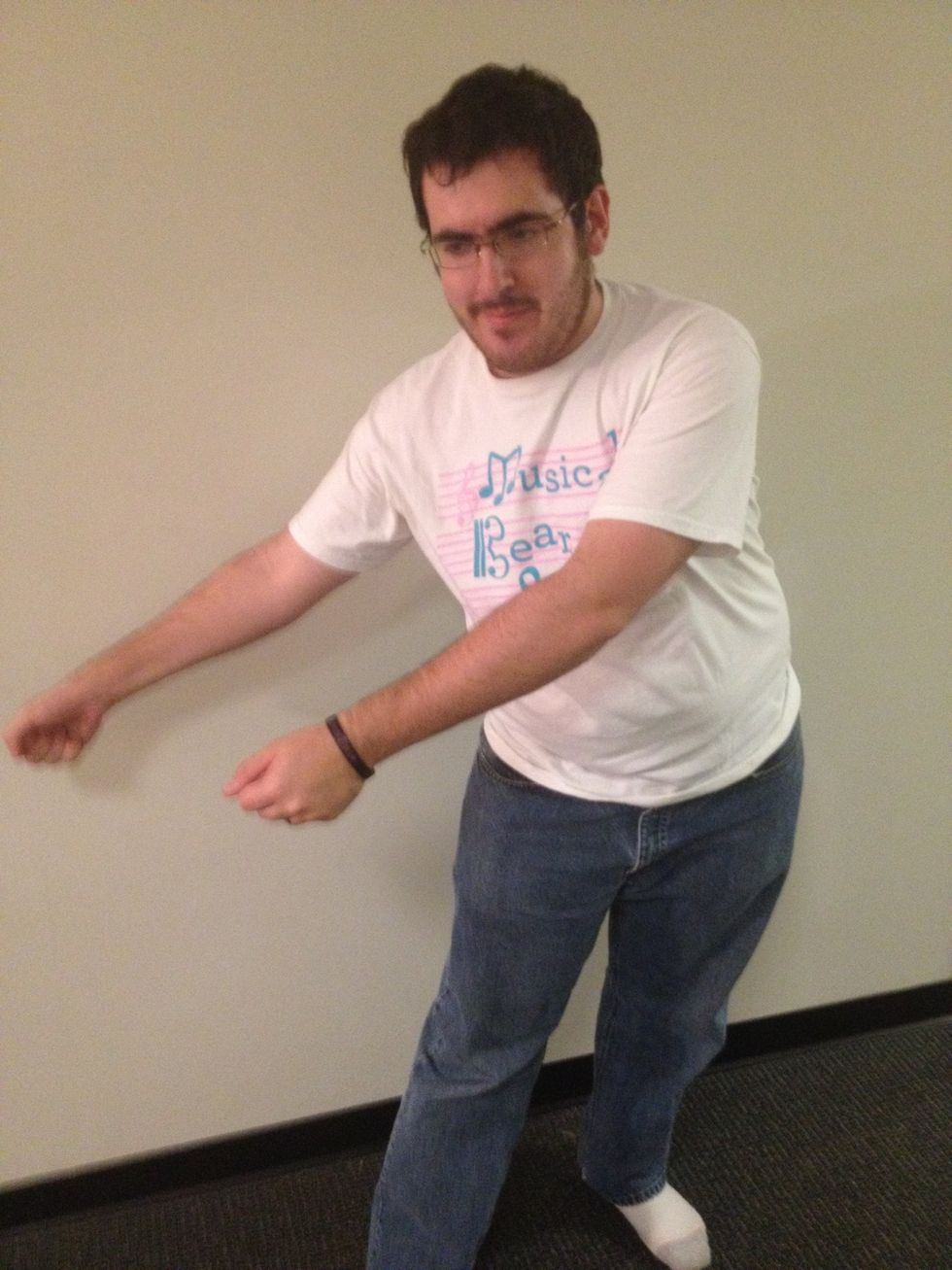 Start by leaning your hips to the right. Curl your hands into fists and position them to your left as shown.