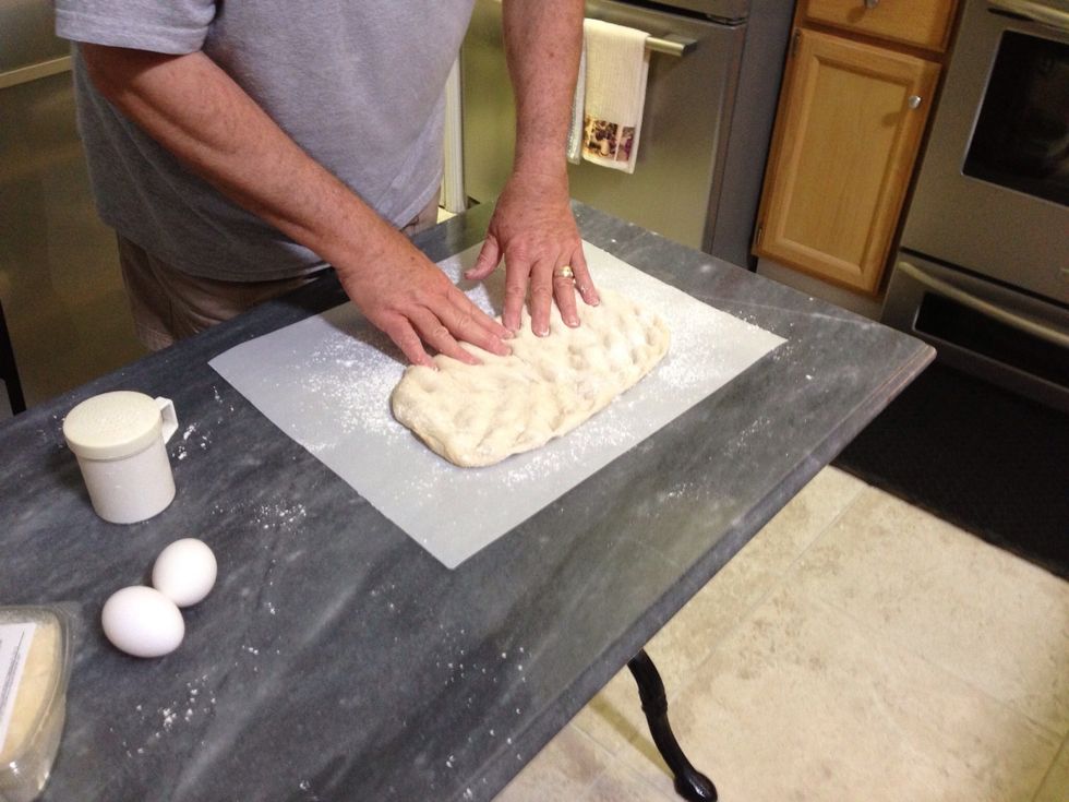 Start by pressing the air out of the dough and flattening it into a rough rectangle.