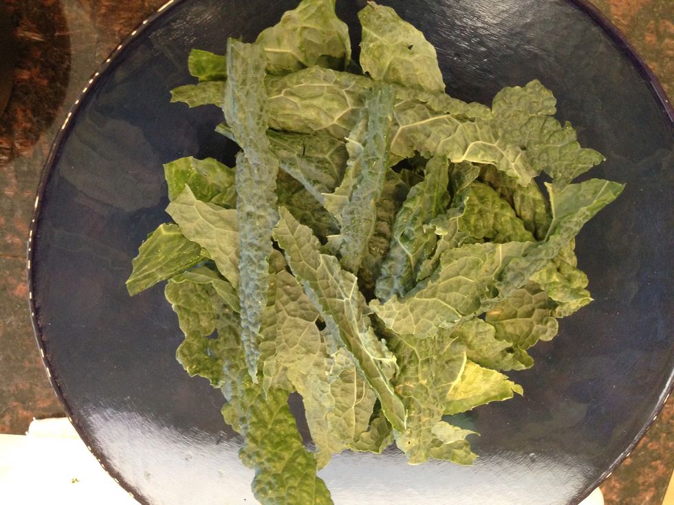 Start by removing the kale leaves from the stem. Place in a bowl and rinse thoroughly with warm water.
