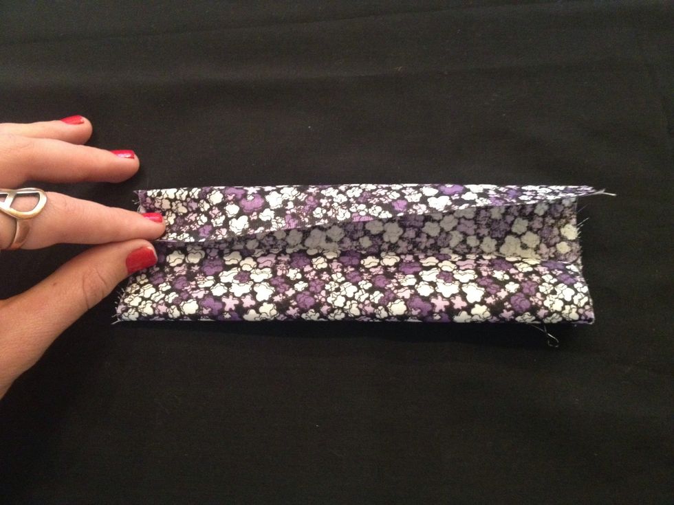 Start by taking the larger piece of fabric and laying it face down on your work surface. Fold the long edges inward so that they meet in the middle and crease the edges.