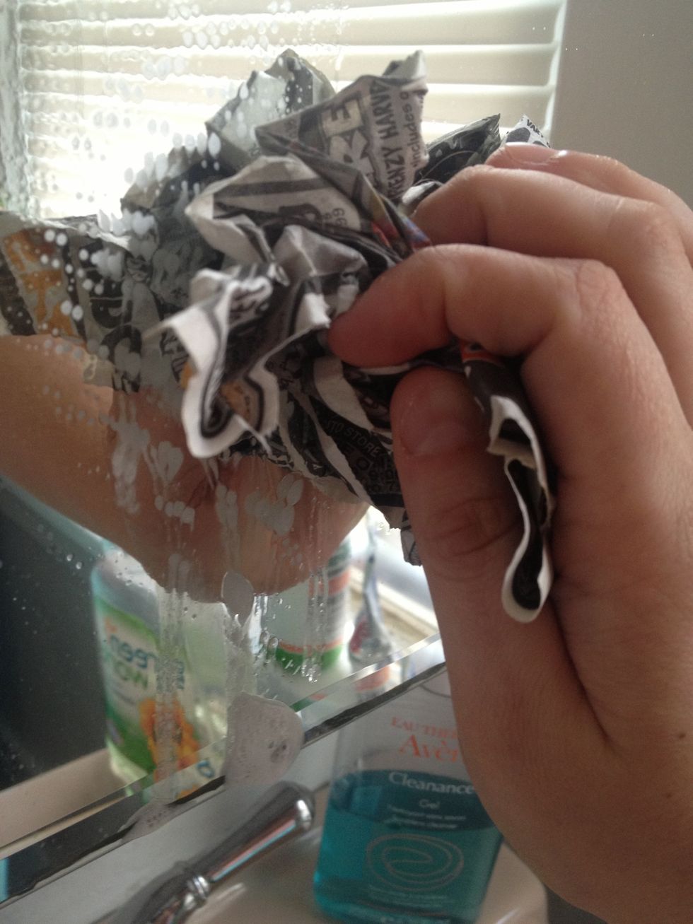 Start cleaning the mirror with the newspaper like you would with a piece of paper towel. Paper towels leave residue, but newspaper won't.