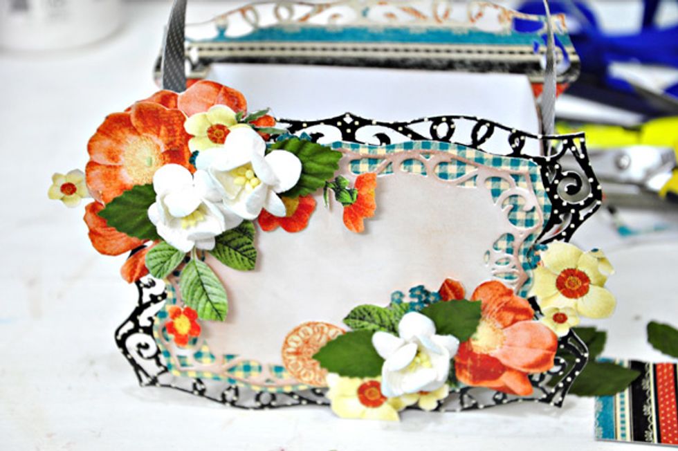 Start embellishing the bag. Add some stickers, chipboards and flowers.