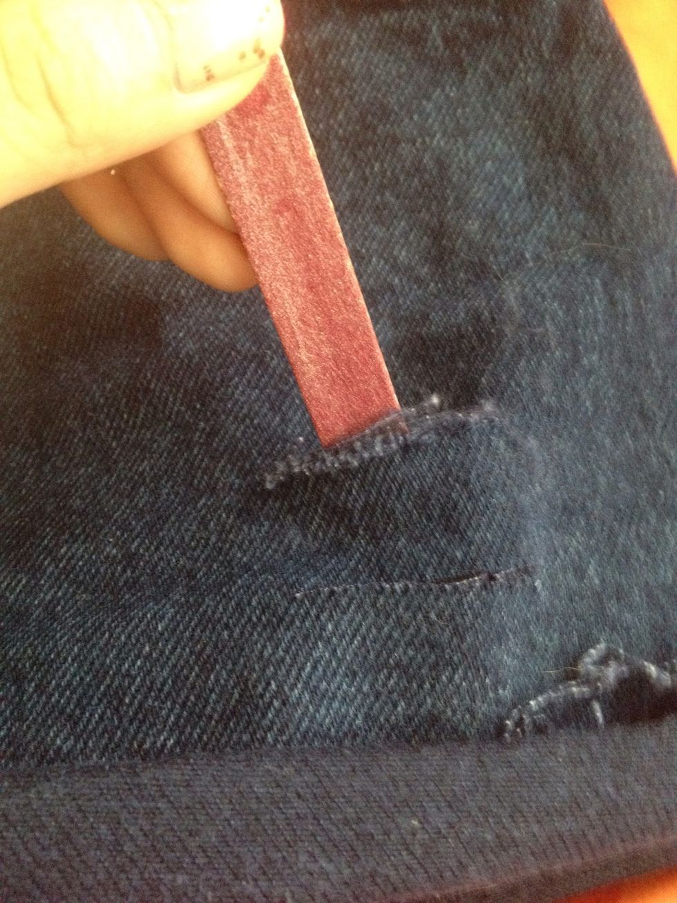 Start filing the cuts on the denim with your nail filer. File top and bottom.