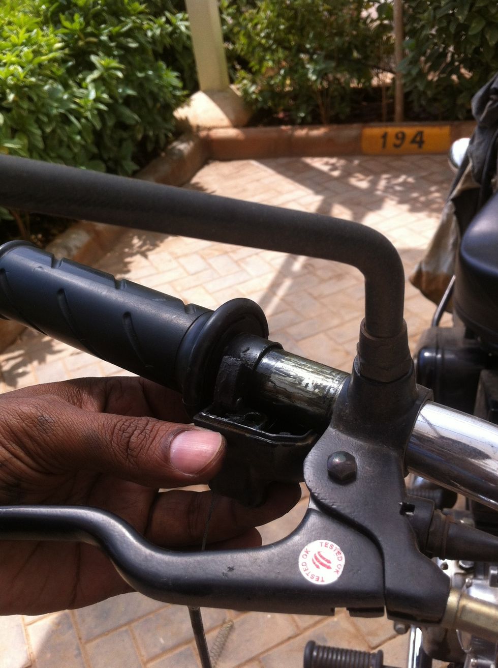 Start fixing the throttle holder by aligning the bottom holder to the handlebar.