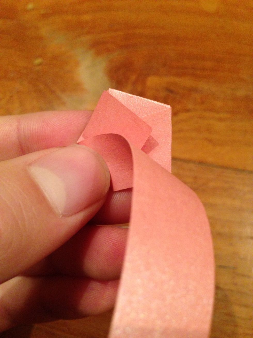 Start folding the strip around the pentagram. Make sure the pentagram remains a pentagram, so don't cross any corners.