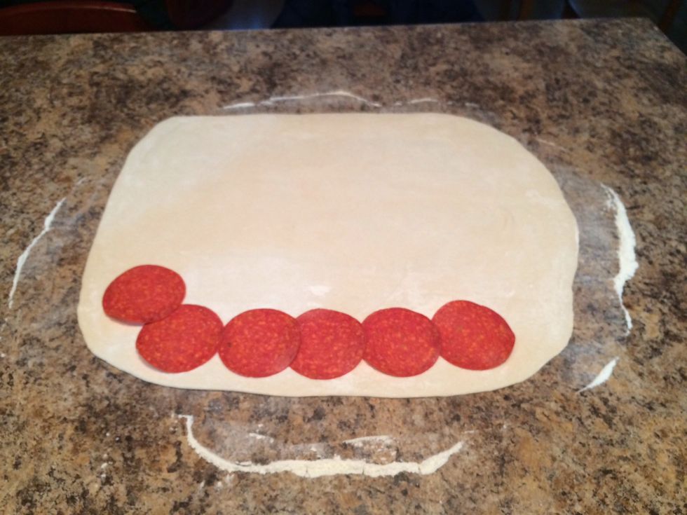 Start laying out the pepperoni. Overlap the ends about 1/4 of an inch or so. Leave 3/4 of an inch of space around the edges.